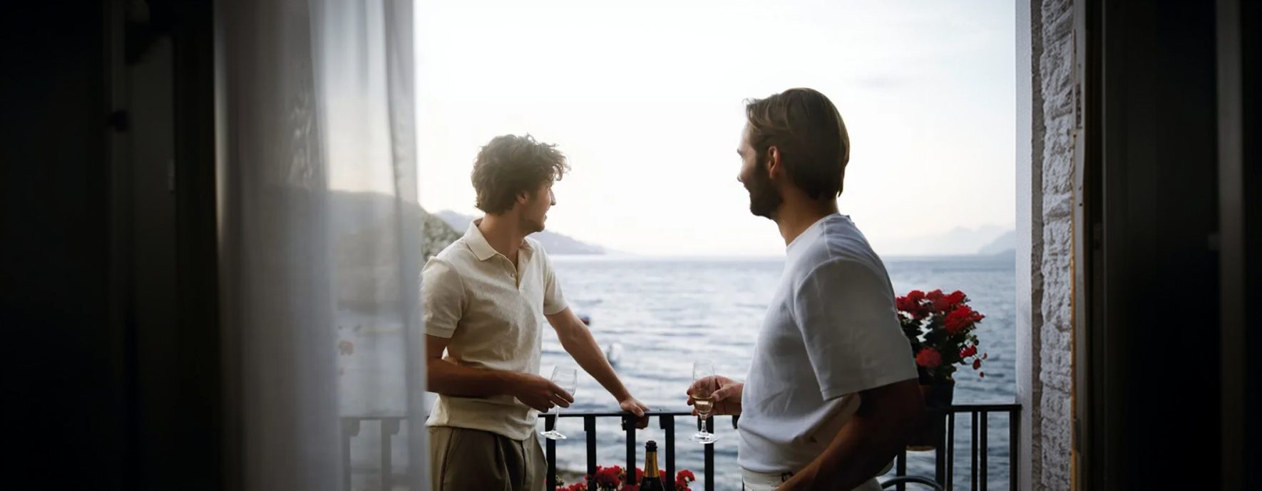 Two people talking on a balcony overlooking the water